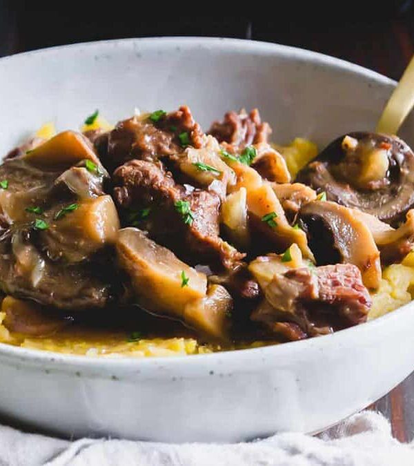 A bowl of beef stew with mushrooms.