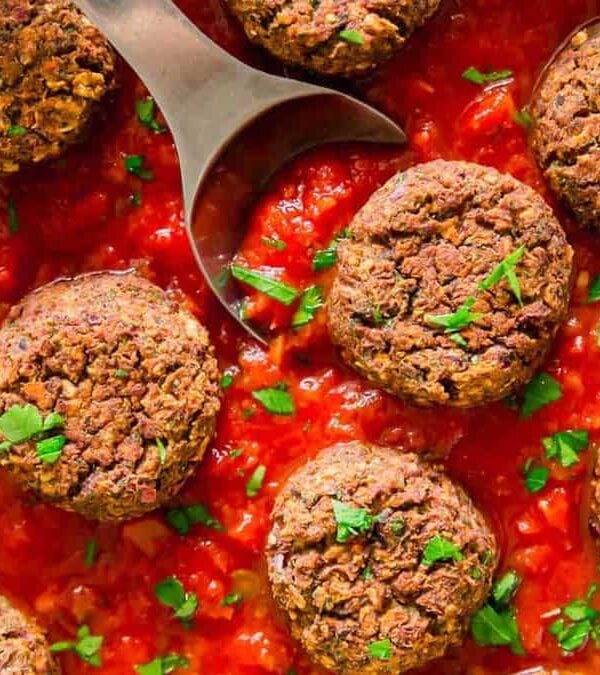Black bean meatballs in tomato sauce with a spoon.