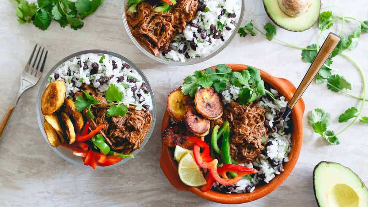 Mexican shredded beef bowls with plantains, rice and beans and peppers.