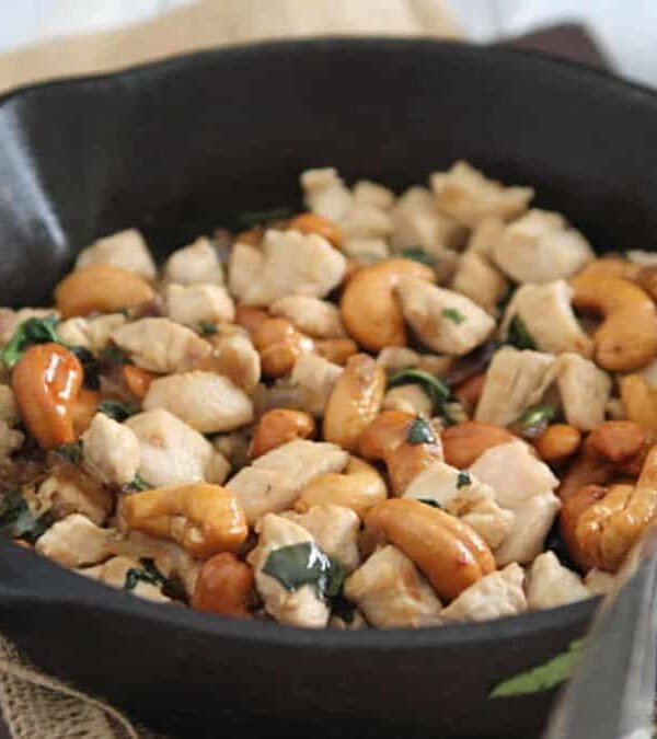 A skillet filled with chicken and cashews.
