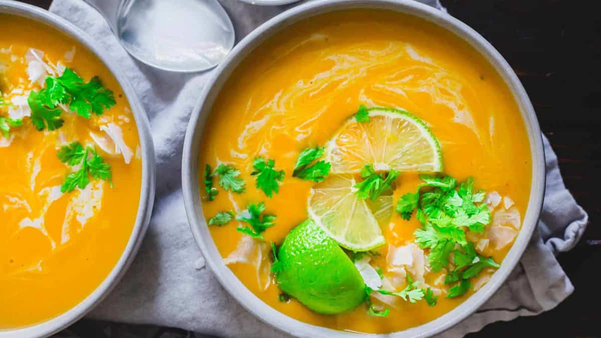 Two bowls of Thai buttercup squash soup with lime and cilantro.