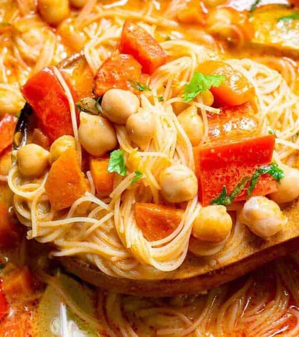A pot of soup with noodles, tomatoes and chickpeas.