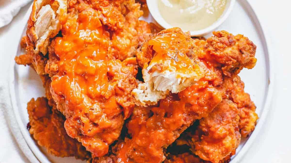 Buffalo chicken tenders on a plate with dipping sauce.