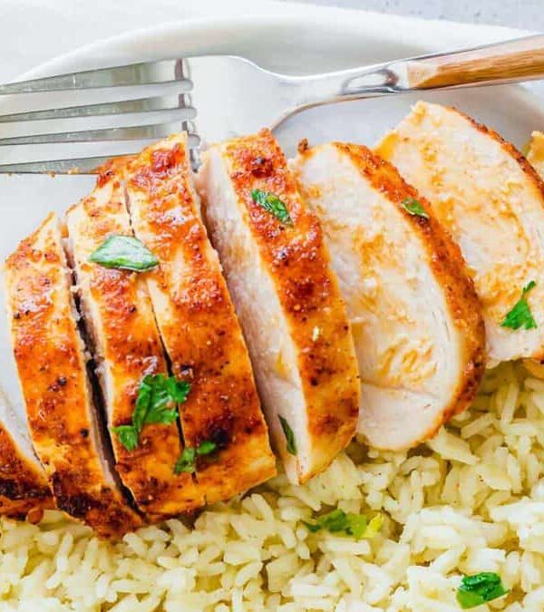 Sliced chicken on a plate with rice and fork.