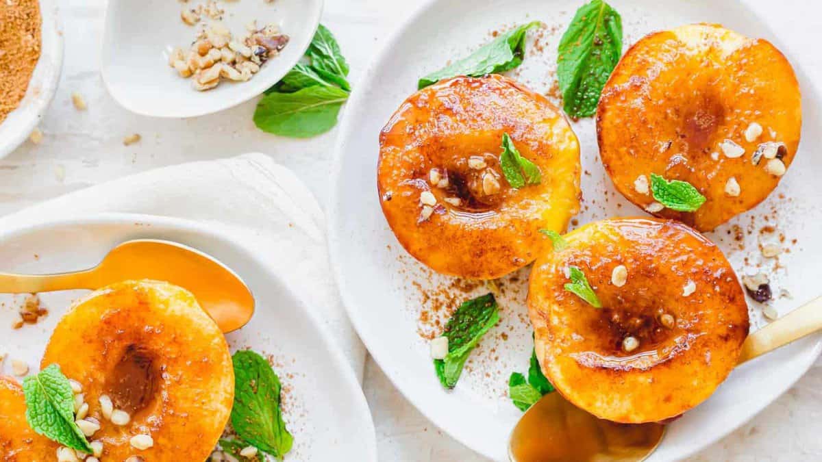 Air fryer peaches on white plates with mint garnish.