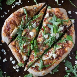 A pizza with cheese and arugula on a plate.