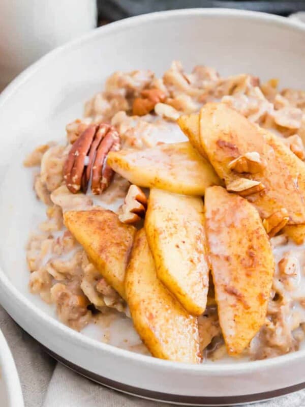 A bowl of oatmeal with apples and pecans.