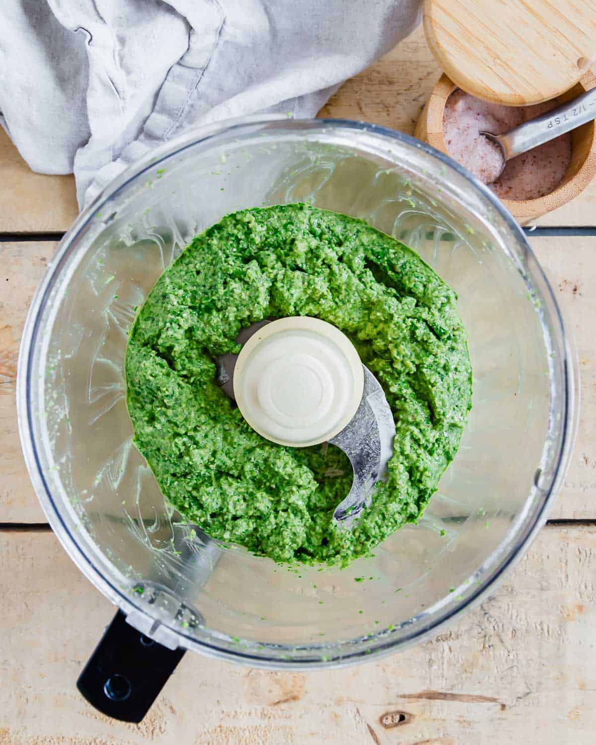 Green arugula pesto in a food processor bowl.