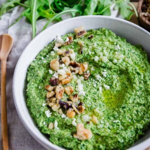 Close up of a bowl of pesto made with arugula with walnuts and grated parmesan.