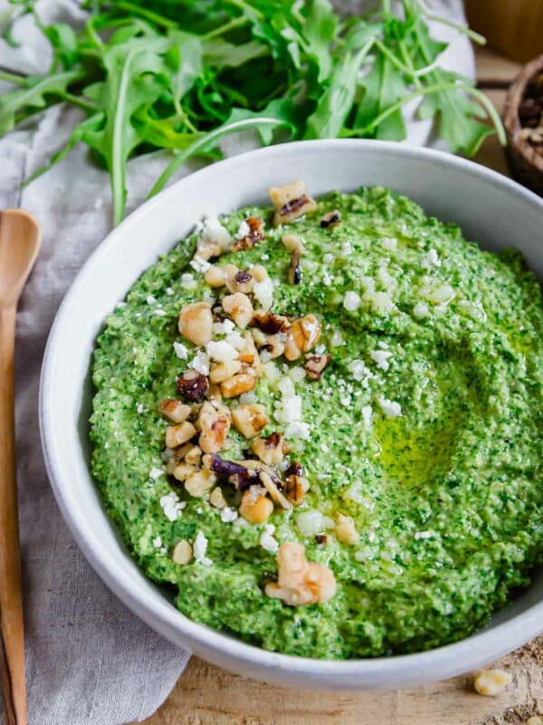 Close up of a bowl of pesto made with arugula with walnuts and grated parmesan.