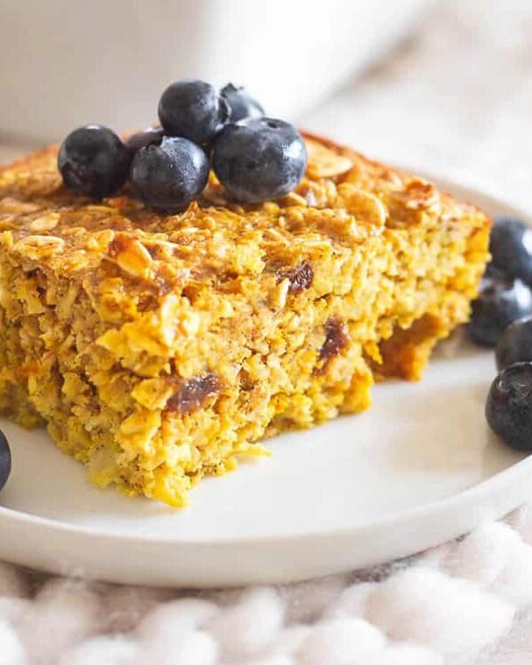 A piece of baked turmeric oatmeal on a plate with blueberries.