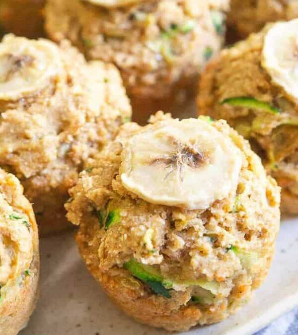 Zucchini muffins on a plate with sliced bananas.