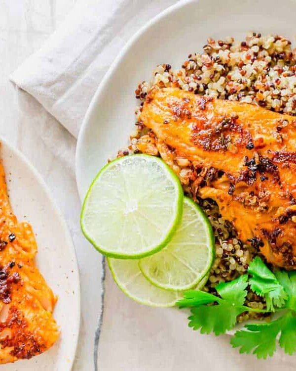 A plate of blackened cod with rice and lime wedges.