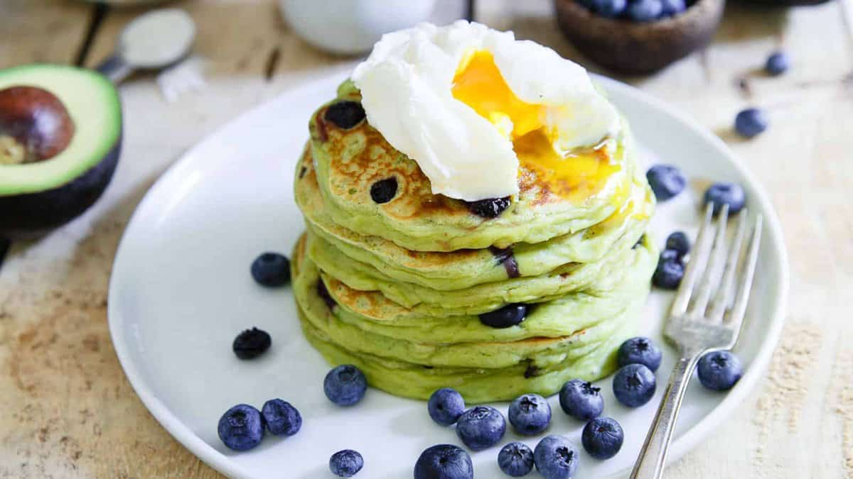 Avocado pancakes with blueberries and a poached egg on top.