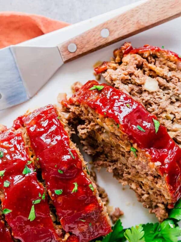 Sliced meatloaf on a white plate with a fork.