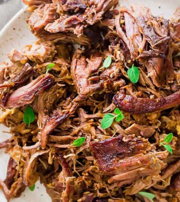 Braised leg of lamb on a white plate.