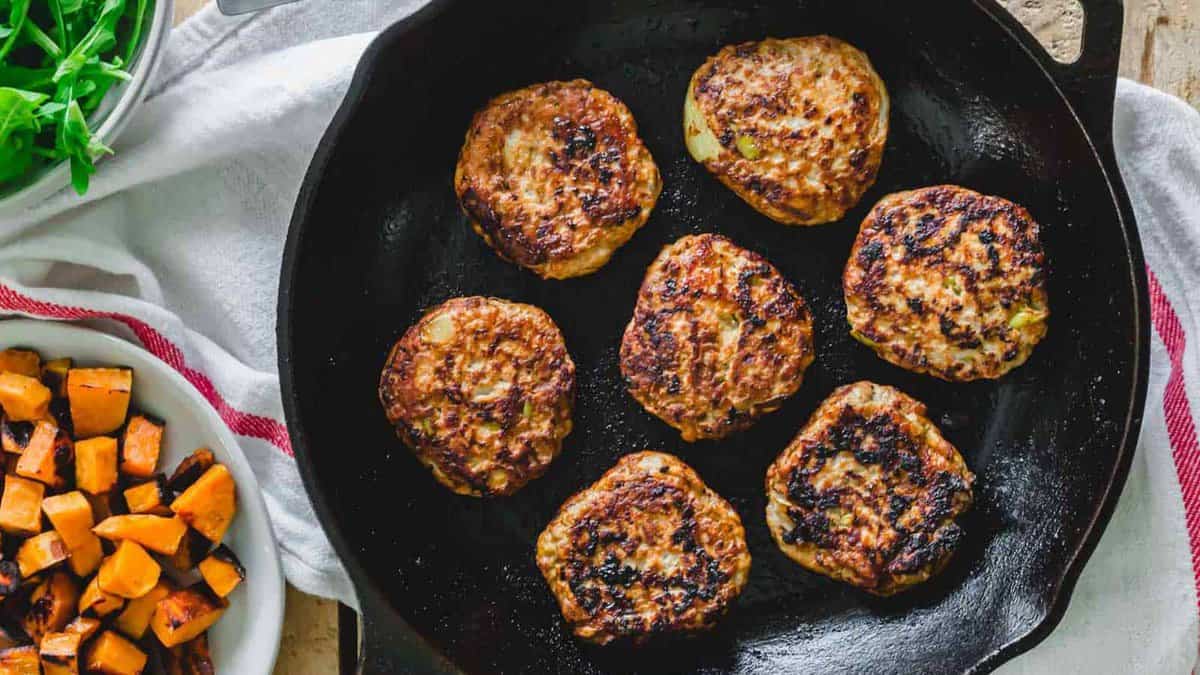 Ground chicken sausage breakfast patties in a cast iron skillet.