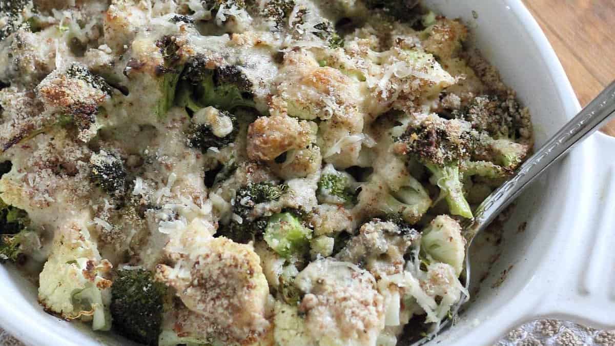 Broccoli cauliflower gratin with serving spoon in a baking dish.