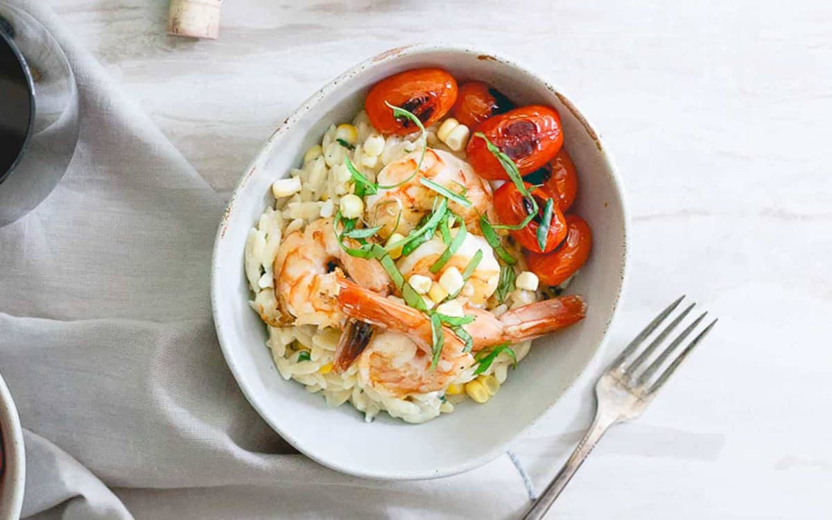 Brown butter shrimp and orzo served with burst cherry tomatoes in a bowl.