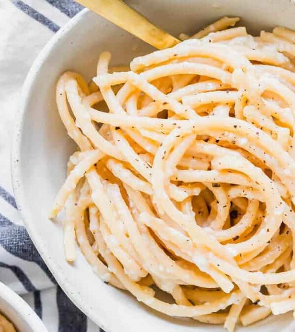 Pasta in a white bowl on a striped towel.