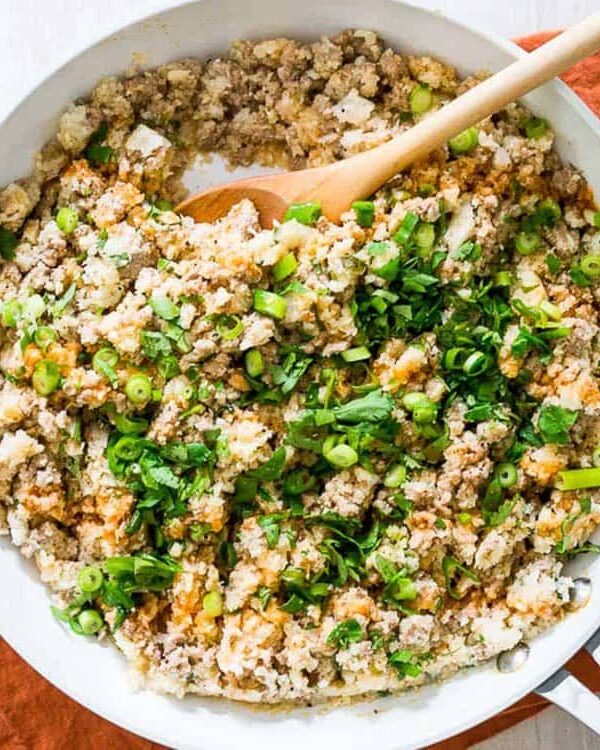 A skillet filled with ground turkey, cauliflower rice and greens.