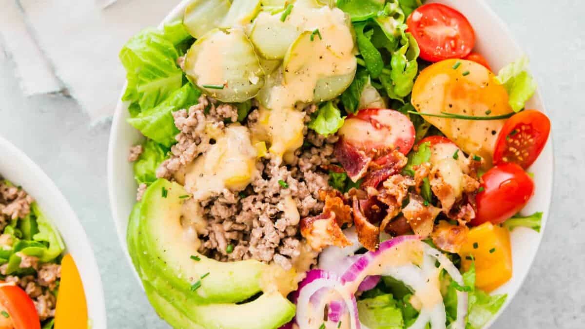 Two burger bowls of salad with lettuce, tomatoes and avocados.
