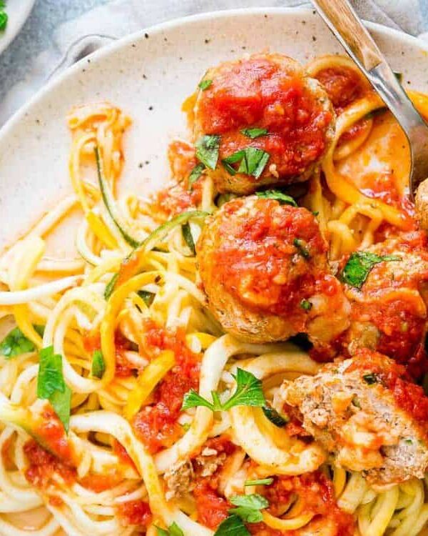 Cheddar cheese stuffed turkey meatballs on a plate with zoodles.