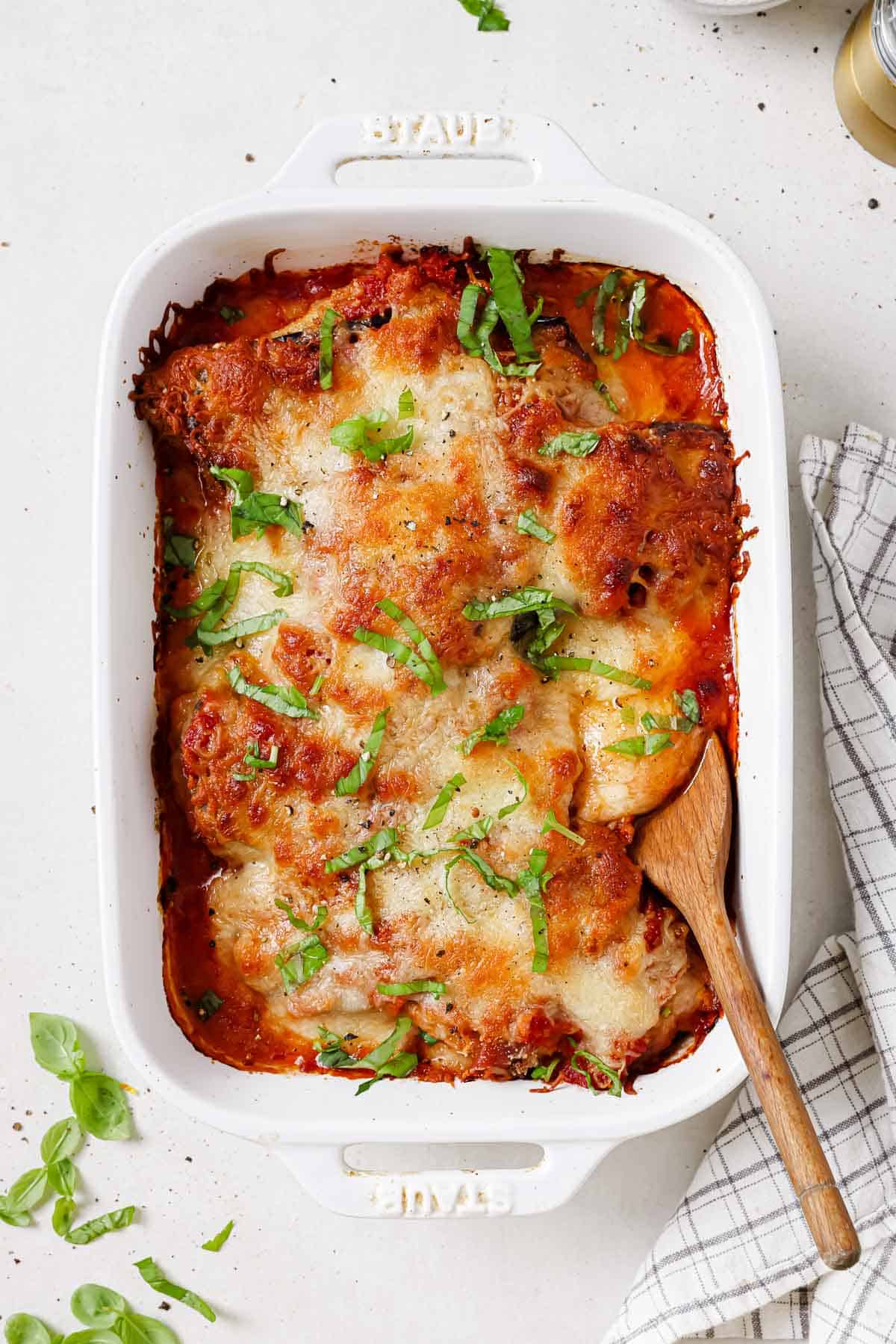 Chicken sorrento in a white baking dish with a wooden spoon.