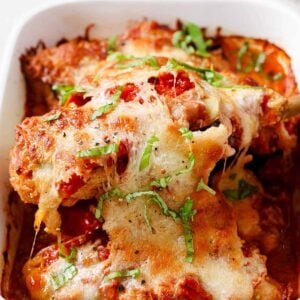 A white baking dish with chicken sorrentino on a serving spoon.