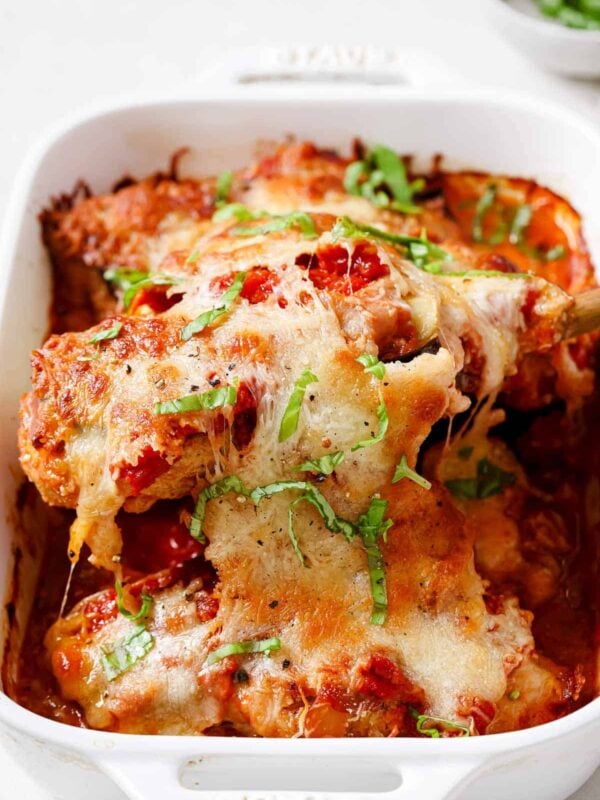 A white baking dish with chicken sorrentino on a serving spoon.