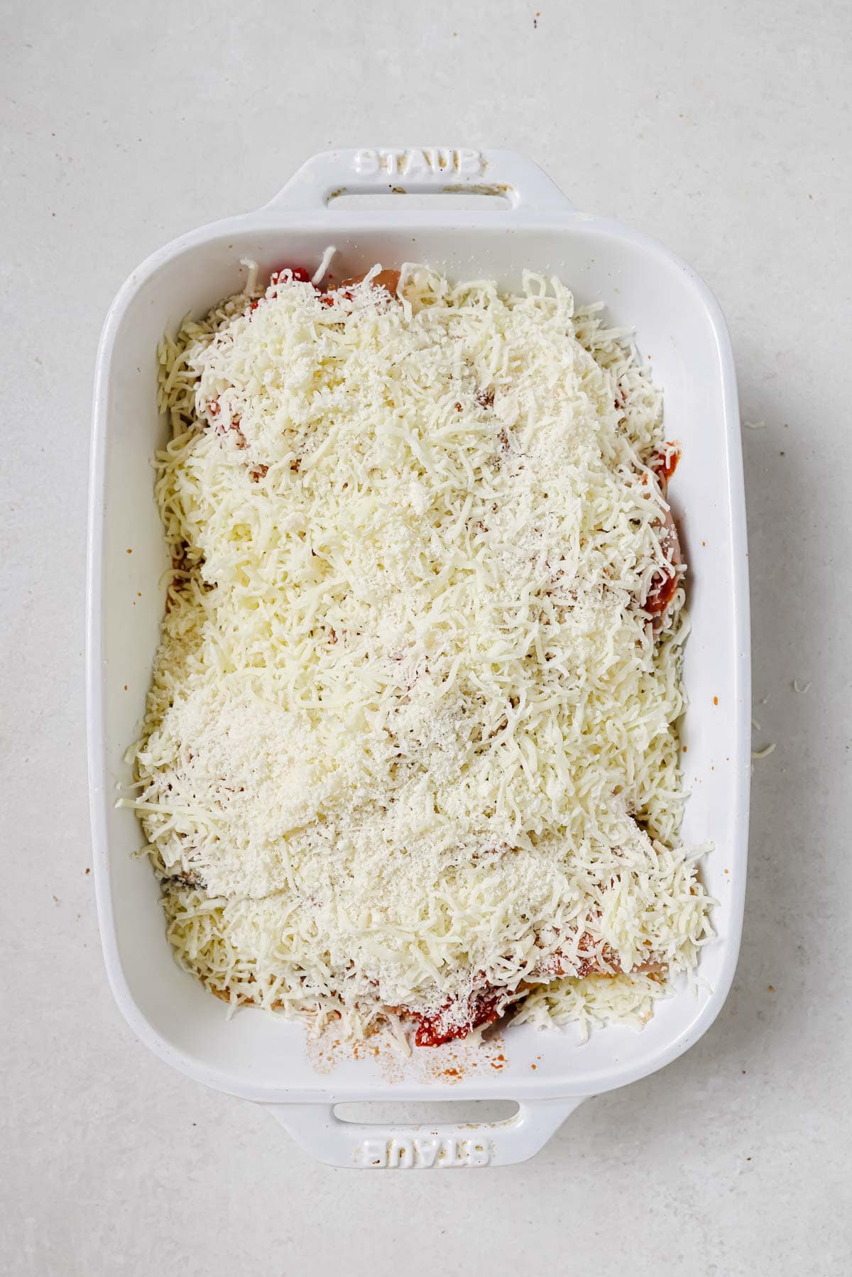 Mozzarella cheese grated on top of chicken sorrentino before baking.