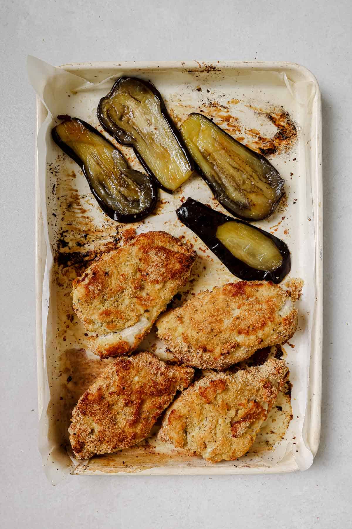 Roasted chicken and eggplant on a baking sheet.