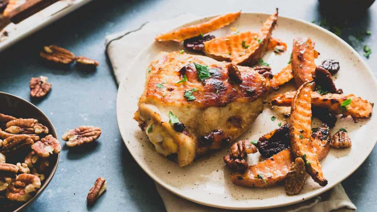 Chicken and sweet potatoes with pecans on a plate.