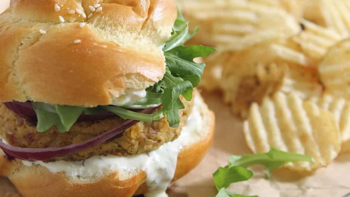 Spicy chickpea bacon burgers with arugula and chips on the side.