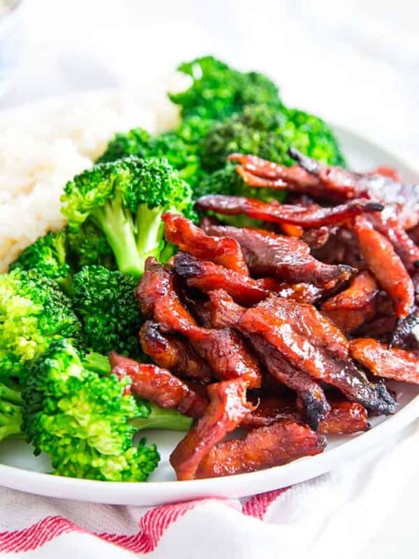 A white plate with broccoli and boneless spare ribs on it.