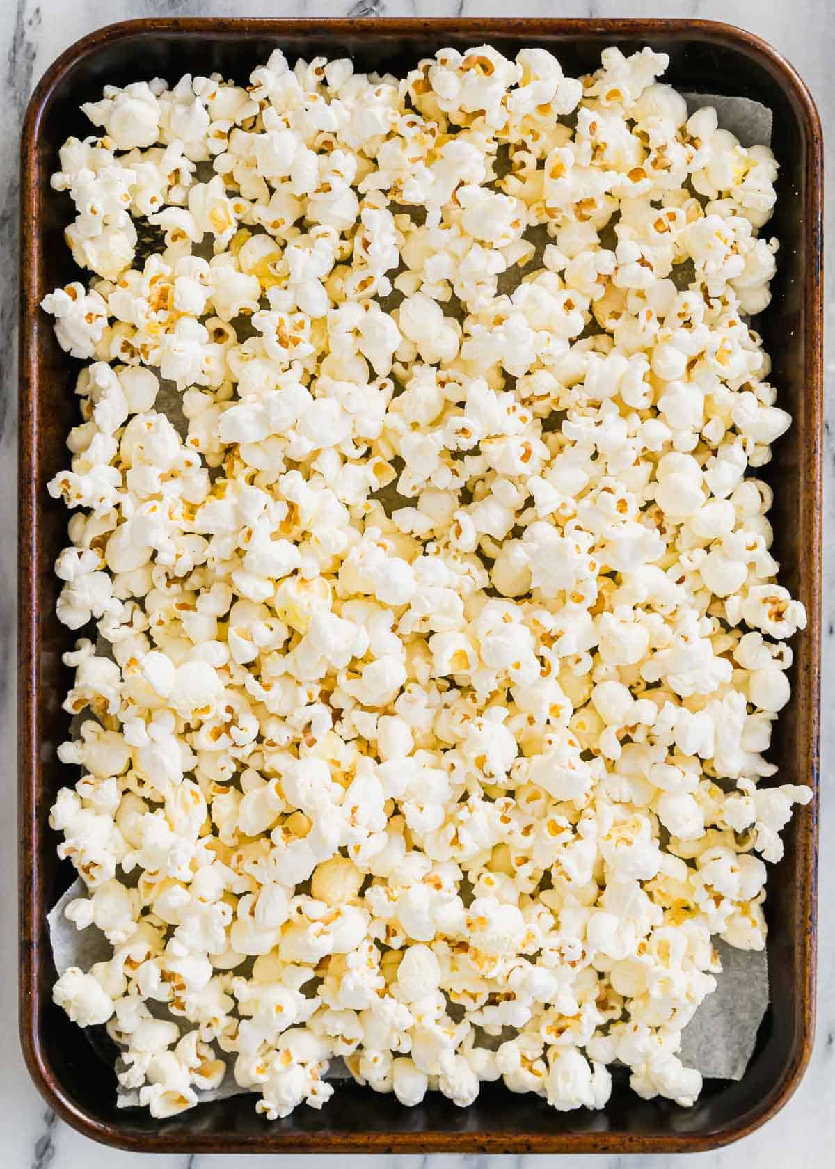 Popcorn in a baking pan on a marble countertop.