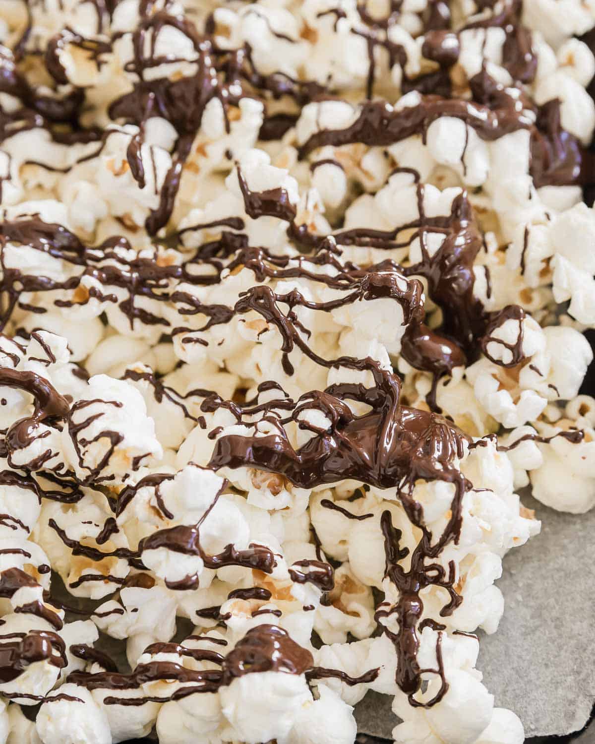 Chocolate drizzled popcorn on a baking sheet.