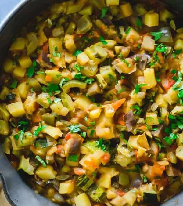 A skillet filled with vegetables and herbs.