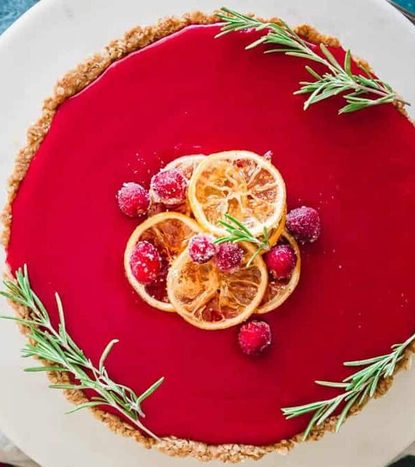A cranberry tart on a plate with rosemary sprigs.