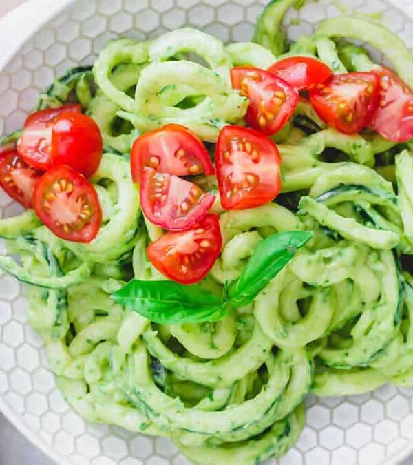 Zucchini noodles with avocado sauce on a white plate.