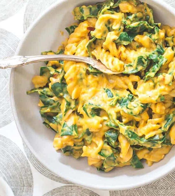 A bowl of pasta with spinach in it.