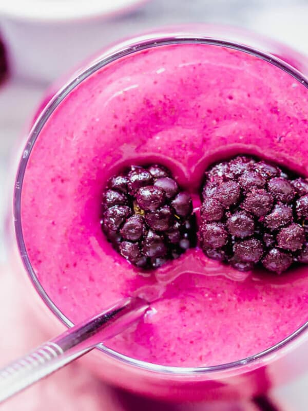 Blackberry smoothie in a glass with a spoon.