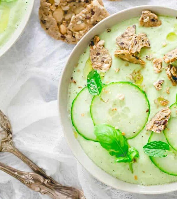 A bowl of cucumber gazpacho soup with a spoon.