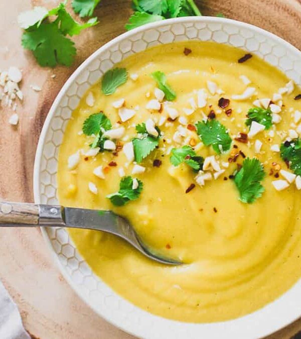 A bowl of soup with a spoon on a wooden table.
