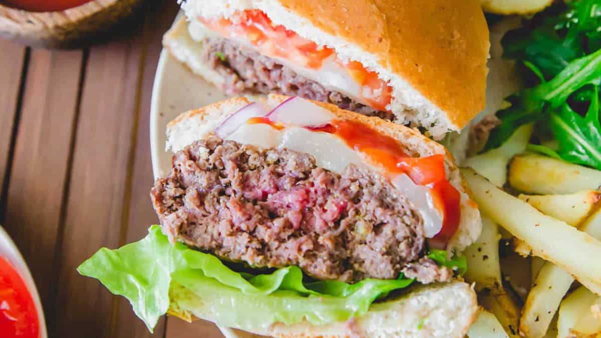 Elk burger sliced in half with cheese, tomato and lettuce on a bun.