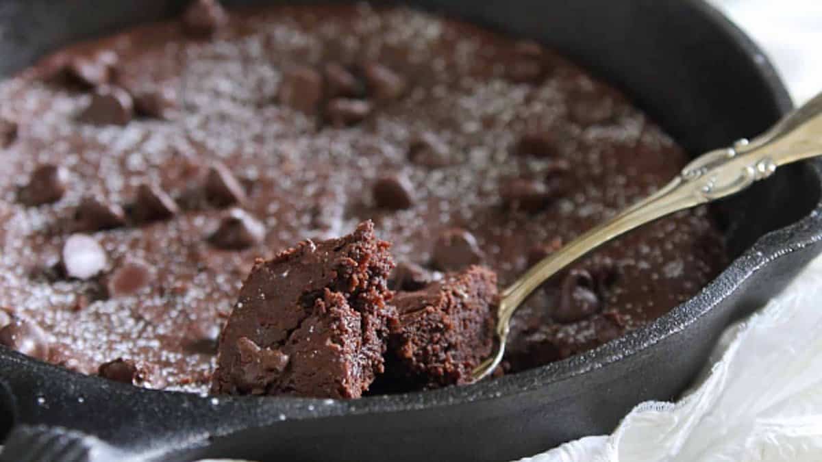 Skillet brownie in a cast iron pan with a spoonful showing.