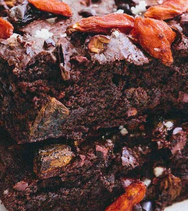 A stack of chocolate brownies with goji berries on top.