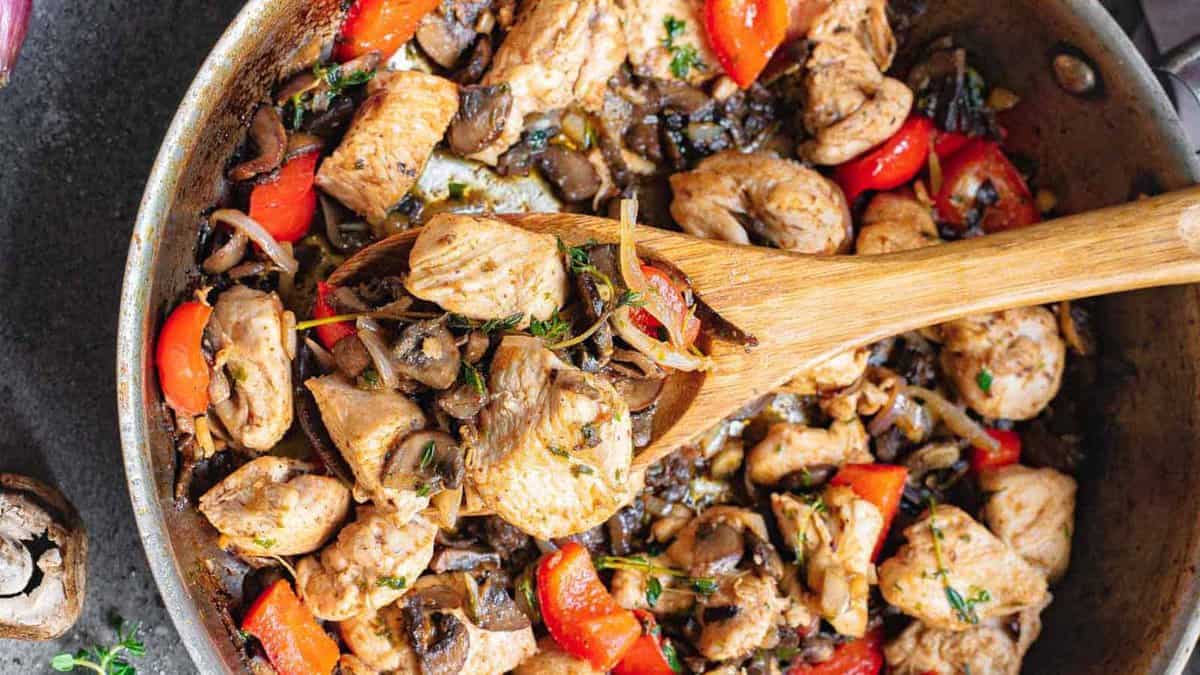 Garlic chicken bites with peppers and mushrooms in a skillet.