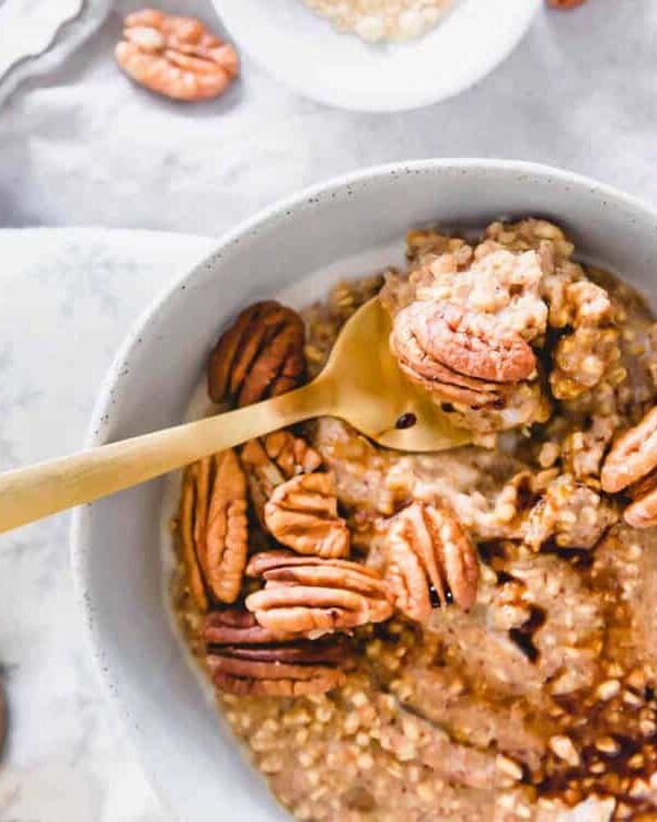 A bowl of gingerbread oatmeal with pecans and a spoon.