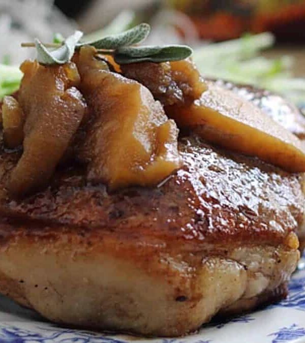 Pork chops with apple sauce on a plate.